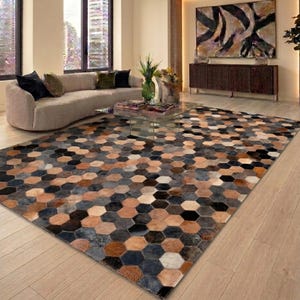 Puede incluir: Una alfombra grande con un patrón geométrico de baldosas hexagonales en varios tonos de marrón, negro, gris y blanco. La alfombra está construida con piezas individuales de material texturizado dispuestas en un diseño de panal.