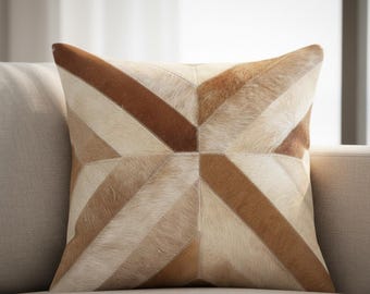 May include: Square decorative pillow with a geometric pattern. The pillow features a patchwork design with various shades of brown and beige, creating a textured appearance. The pillow is placed on a neutral-colored sofa.