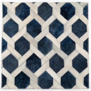 May include: A square rug crafted from cowhide patches featuring a geometric pattern of dark blue hexagons interconnected by light gray strips. The surface has a visible hair-on-hide texture with stitched seams between each individual piece.