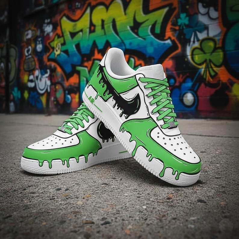 Puede incluir: Zapatillas blancas y verdes con un dise&ntilde;o &uacute;nico. Los zapatos presentan una base blanca con detalles verdes que parecen gotear. Los logotipos negros de Nike swoosh son visibles en los laterales. Los cordones son verdes, sobre un fondo de graffiti.