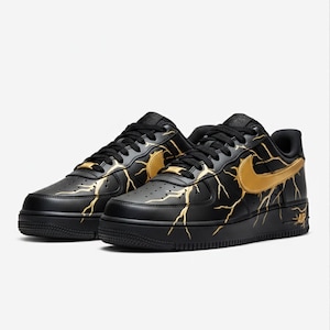 May include: Black leather sneakers with gold lightning bolt designs and a gold Nike swoosh. The shoes have black laces and soles, with the word "AIR" in gold on the side.