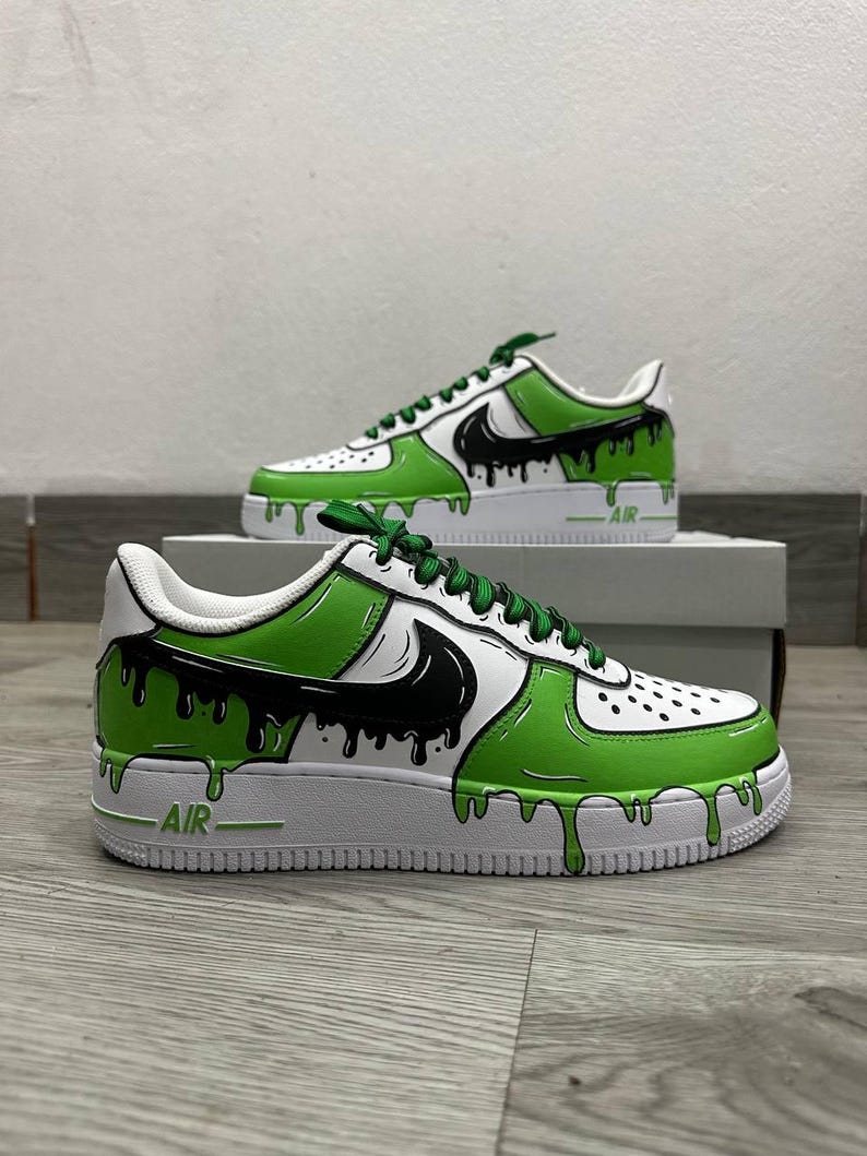 Puede incluir: Zapatillas personalizadas blancas y verdes con detalles en negro. Las zapatillas presentan un dise&ntilde;o de goteo verde y negro en la parte superior e intermedia de cuero blanco. El logo de Nike es negro. Cordones verdes.