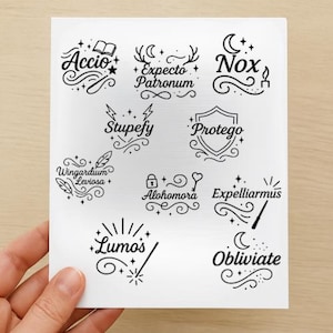 Op de afbeelding: Een vel zwart-witte stickers met verschillende spreuken uit een populaire fantasyserie. De stickers bevatten zinnen als "Accio", "Expecto Patronum" en "Lumos", met decoratieve krullen en illustraties.
