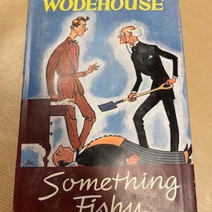 May include: Vintage hardcover book titled "Something Fishy" by P.G. Wodehouse. The cover features an illustration of three men in a humorous scene, with a blue sky background and a maroon border.