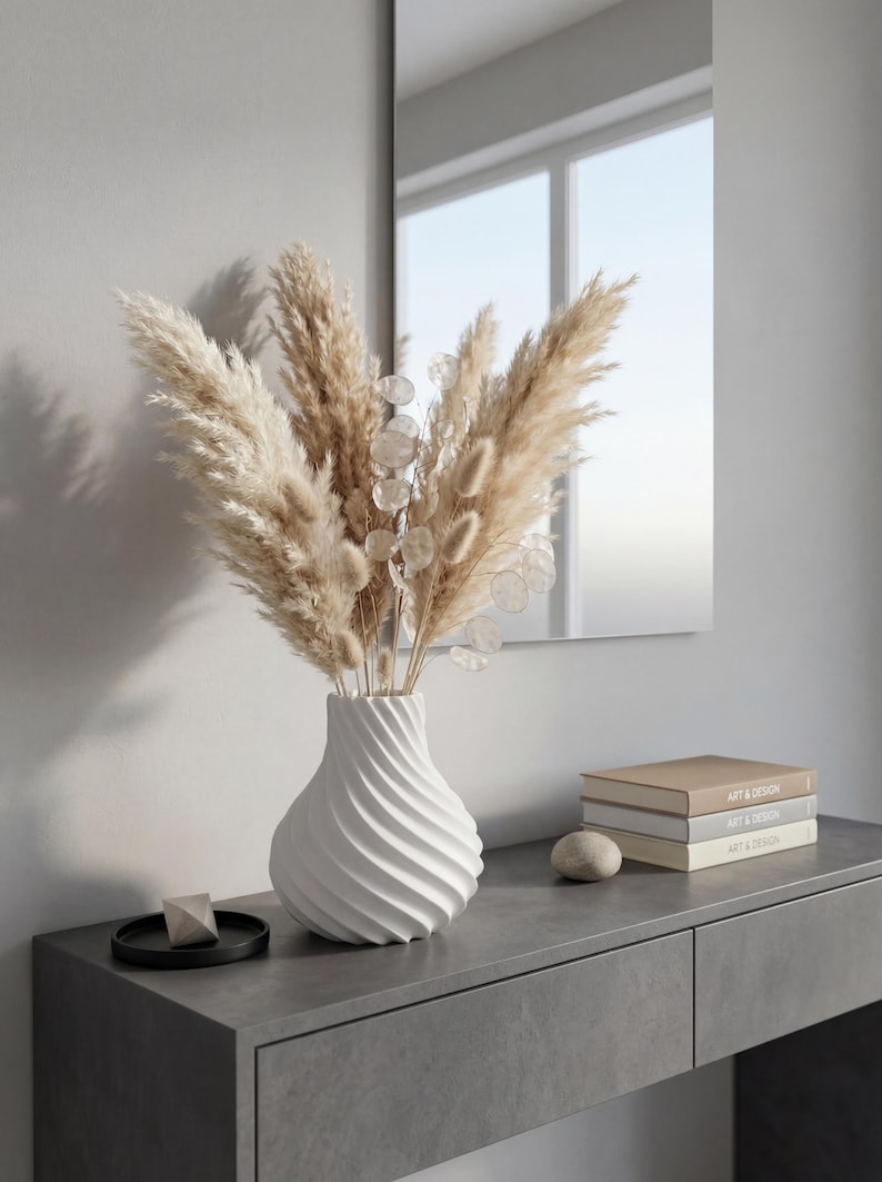 White twisted spiral ribbed vase with dried pampas and lunaria bouquet – modern 3D printed PLA swirling texture. Minimalist Scandinavian Japandi home decor on grey console with mirror and books
