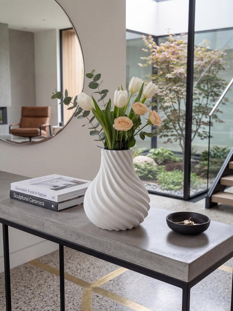 White twisted spiral ribbed vase with fresh tulips and eucalyptus – modern 3D printed PLA swirling diagonal texture. Minimalist Scandinavian Japandi home decor on concrete console with mirror and fresh flowers