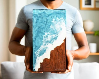 May include: A rectangular wooden art piece with a blue and white resin wave design on the top half and a brown wood grain on the bottom half. The piece is held by a person. The text "Artshrubs" is visible on the bottom right.