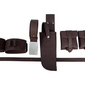May include: A brown leather belt and holster set. The set includes a belt with a silver buckle, two cartridge holders, a knife sheath, and two small pouches. The items are arranged on a white background.