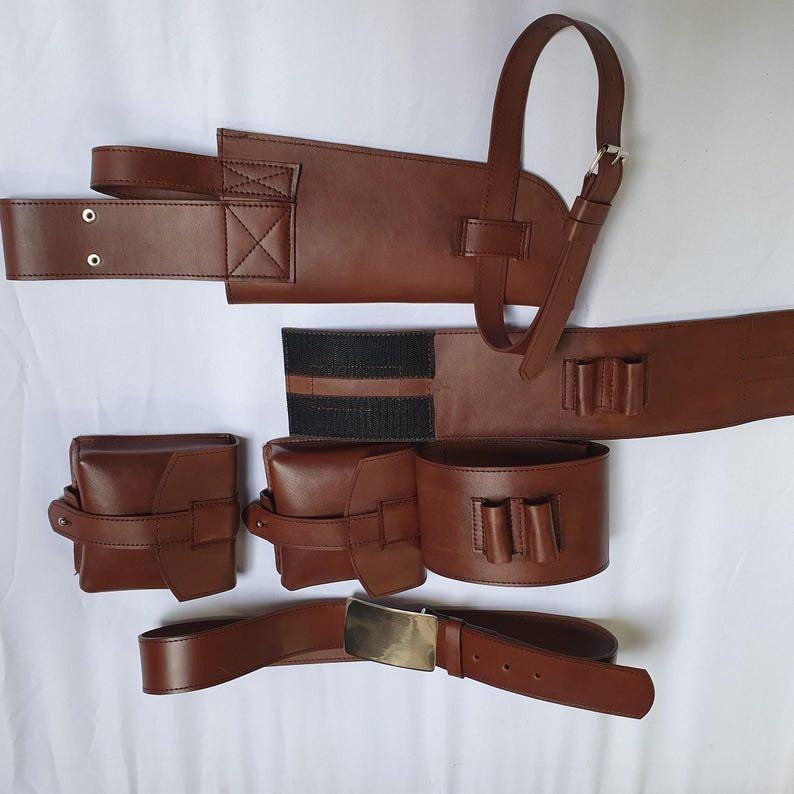 May include: A brown leather utility belt set, featuring a belt with a rectangular buckle, two pouches, a holster, and a bandolier-style strap. The set includes a belt with a rectangular buckle, two pouches, a holster, and a bandolier-style strap.