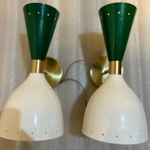 May include: Two mid-century modern wall sconces. Each has a white, bell-shaped shade with small holes. The top is a dark green cone with white dots. Gold-coloured metal accents and mounting plates complete the design. Suitable for UK homes.