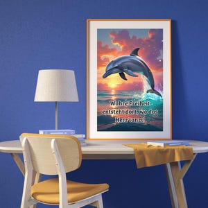 May include: A framed art print featuring a dolphin leaping from ocean waves against a sunset sky. The artwork has a vibrant color palette of blues, oranges, and yellows. Text on the print reads, "True freedom arises where the heart dances!"