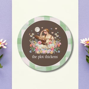 May include: A greeting card with a circular design featuring a vintage illustration of a woman surrounded by flowers and butterflies. The design is set against a brown background with the text "the plot thickens". The circle is framed by a green and white gingham pattern.