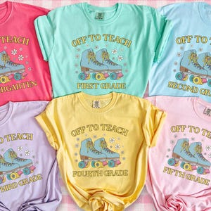 May include: A collection of six colorful t-shirts with the text "OFF TO TEACH" and grade levels Kindergarten through Fifth Grade. Each shirt features a graphic of roller skates in a retro style, with a pink and white checkered background.