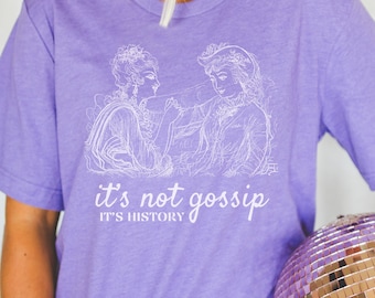 May include: Purple t-shirt with a white graphic of two women in a vintage style illustration. The text "it's not gossip it's history" is printed below the graphic.