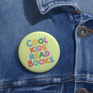Pode incluir: Um botão verde com o texto "COOL KIDS READ BOOKS" em letras coloridas com estrelas ao redor do texto.