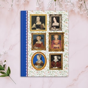 May include: A notebook cover with a floral pattern and six framed portraits of women in historical attire. The portraits are in gold frames with ornate details. The cover is blue with a scalloped edge.