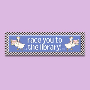 May include: A rectangular sign with a blue background and a brown and white checkered border. The sign features two cartoon geese carrying books, with the text "race you to the library!" in white.