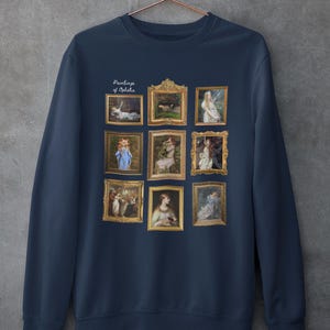 May include: Navy blue sweatshirt with a print of nine framed paintings of Ophelia. The text "Paintings of Ophelia" is printed above the paintings.