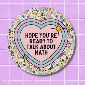 May include: A round sticker with a floral border and a heart-shaped center. The heart is pink with a teal outline and the text "HOPE YOU'RE READY TO TALK ABOUT MATH". Two yellow starbursts are on the heart. The background is a light purple tile.