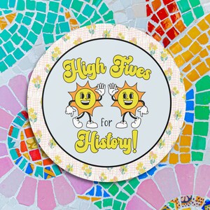 May include: A round, blue and white sticker with two yellow cartoon suns giving each other a high five. The text "High Fives for History!" is written in yellow letters.