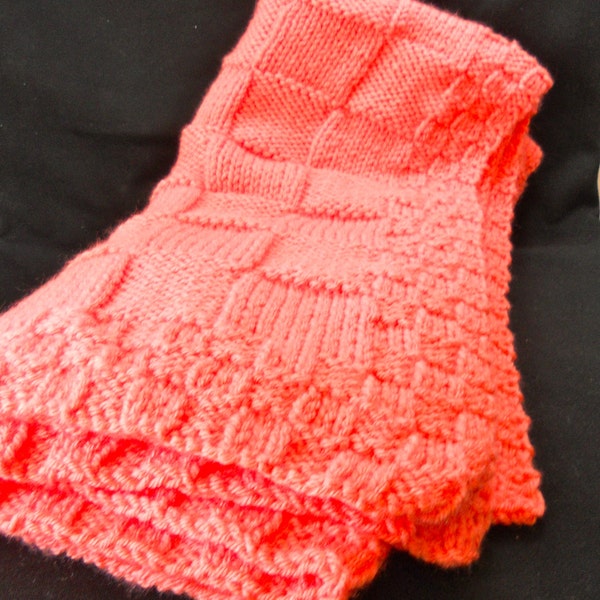 Manta de bebé color coral tejida a mano y muy suave.