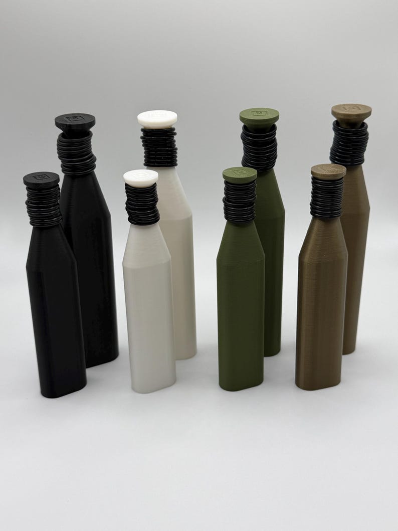 May include: A collection of eight bottles in various colors, including black, white, olive green, and brown. Each bottle has a black, ridged neck and a matching cap. The bottles are arranged on a white surface.