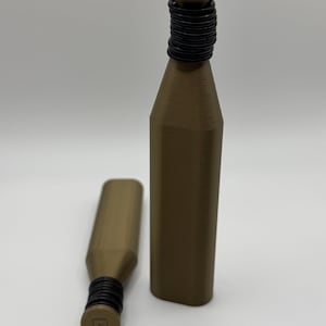 May include: Two brown bottle stoppers with black rubber rings around the neck. One stopper is upright, the other is lying down. The stoppers have a cylindrical shape with a flat top and bottom.