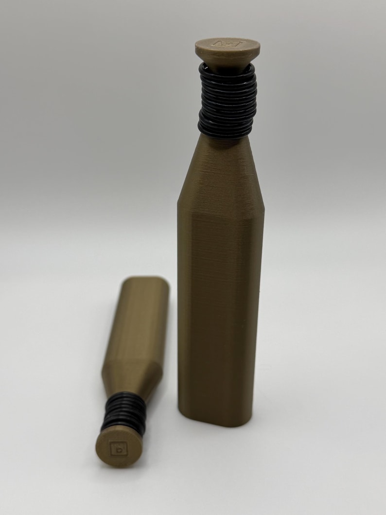 May include: Two brown bottle stoppers with black rubber rings around the neck. One stopper is upright, the other is lying down. The stoppers have a cylindrical shape with a flat top and bottom.