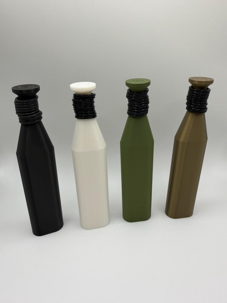 May include: Four bottle stoppers in black, white, olive green, and bronze. Each stopper has a cylindrical top and a black, ridged neck. The bottles have a simple, geometric design, suitable for wine or other beverages.