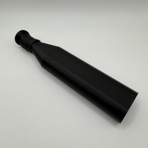 Puede incluir: Un tap&oacute;n de botella negro con un cuello acanalado y un cuerpo largo y rectangular. El tap&oacute;n est&aacute; hecho de un material s&oacute;lido y opaco y est&aacute; dise&ntilde;ado para encajar en una abertura de botella. El dise&ntilde;o es simple y moderno.