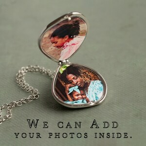 Peut inclure: Collier avec un m&eacute;daillon argent&eacute; &agrave; deux compartiments ovales, chacun contenant une photographie couleur. Le compartiment sup&eacute;rieur montre un enfant en rose, et le bas une m&egrave;re et un enfant. Le texte "WE CAN ADD YOUR PHOTOS INSIDE" est en bas.