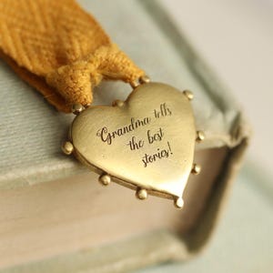 May include: A gold heart-shaped bookmark with the inscription "Grandma tells the best stories!" attached to a yellow ribbon.
