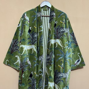 May include: Green velvet kimono with a jungle-themed pattern. The design features white leopards, zebras, toucans, and other birds amidst palm trees and foliage. The interior lining has vertical white and green stripes.