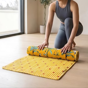 Peut inclure: Un tapis d'exercice jaune à la surface texturée et côtelée. Le tapis présente un motif de palmiers verts et de toucans sur la partie enroulée, tandis que la section plate affiche un motif répétitif de petits cœurs rouges et de rayures blanches.