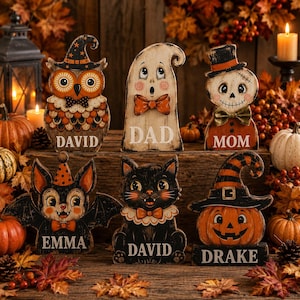 Könnte beinhalten: Sechs hölzerne Halloween-Tischdekorationen in Form einer Eule, eines Geistes, eines Skeletts, einer Fledermaus, einer schwarzen Katze und eines Kürbisses. Jede Figur ist festlich bemalt und mit einem Namen oder Titel versehen: David, Dad, Mom, Emma, David und Drake.
