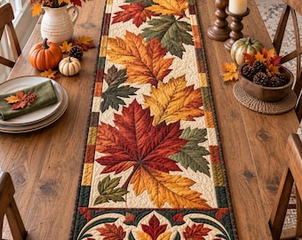 Puede incluir: Un camino de mesa acolchado rectangular con un patrón de hojas otoñales en tonos rojo, naranja, amarillo y verde. El diseño incluye grandes hojas de arce sobre un fondo crema con un borde decorativo de hojas más pequeñas.