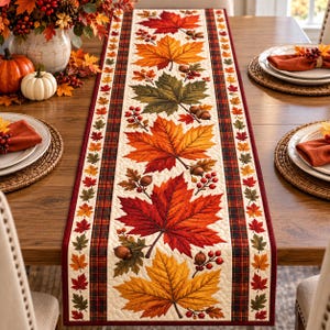 Puede incluir: Un camino de mesa rectangular con un panel central de color crema decorado con grandes y vibrantes hojas de arce otoñales en tonos rojos, naranjas y amarillos, acentuado con bellotas y bayas, enmarcado por bordes de tela a cuadros y rojo oscuro.