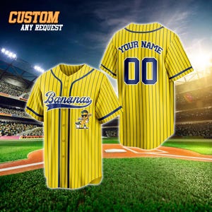 May include: Yellow baseball jersey with vertical navy blue stripes. The jersey features the word "Bananas" in navy blue script on the front, along with a cartoon banana character. The back of the jersey has the text "YOUR NAME" above the number "00". The text "CUSTOM ANY REQUEST" is at the top.