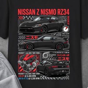 May include: Black t-shirt featuring a graphic design of a Nissan Z Nismo RZ34 car. The design includes illustrations of the car, engine specifications, and Japanese text. The shirt also has the Dualt logo.