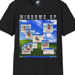 Puede incluir: Camiseta negra con un diseño temático de Windows XP. El diseño incluye el texto "WINDOWS XP" en plateado, junto con un collage de mujeres en bikini en ventanas simuladas de Internet Explorer. La camiseta tiene cuello redondo y mangas cortas.