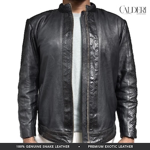 Könnte beinhalten: Schwarze Lederjacke mit Schlangenleder-Akzenten. Die Jacke hat einen Reißverschluss und einen Stehkragen. Die Ärmel und die Vorderteile weisen ein strukturiertes Schlangenmuster auf. Die Jacke ist mit "CALDERI LEATHER GOODS" gekennzeichnet.