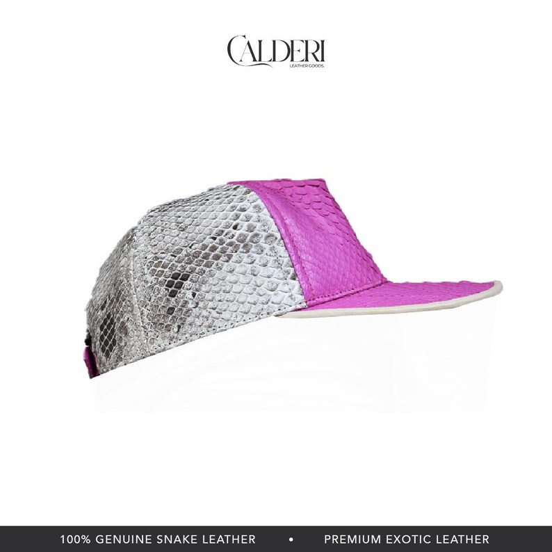 May include: A baseball cap featuring a snakeskin pattern and a vibrant pink peak. The cap is made from genuine snake leather. The brand name "CALDERI" is visible at the top.