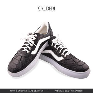 Puede incluir: Zapatillas deportivas negras y blancas con textura de piel de serpiente. Los zapatos tienen cordones blancos, una franja blanca en el lateral y suela blanca. La marca "CALDERI" está en la parte superior.