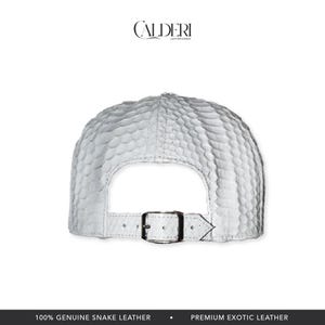 May include: White snake leather baseball cap with a textured design. The cap has a curved peak and an adjustable strap with a metal buckle. The brand name "CALDERI LEATHER GOODS" is visible at the top.