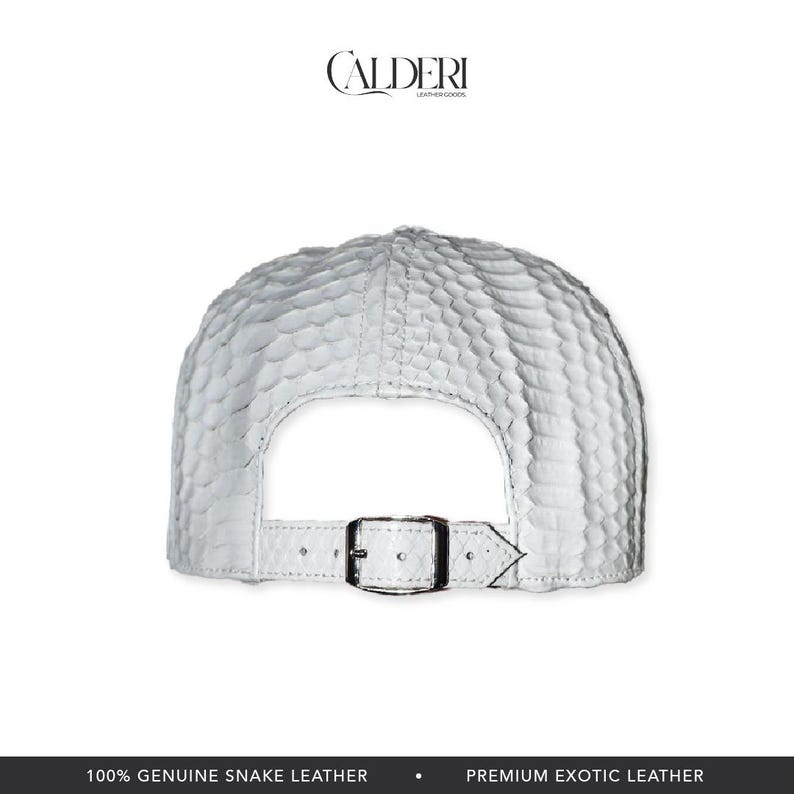 May include: White snake leather baseball cap with a textured design. The cap has a curved peak and an adjustable strap with a metal buckle. The brand name "CALDERI LEATHER GOODS" is visible at the top.