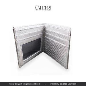 May include: Open white snake leather wallet with multiple card slots and a clear ID window. The wallet is made of genuine snake leather and features the brand name "CALDERI" at the top.