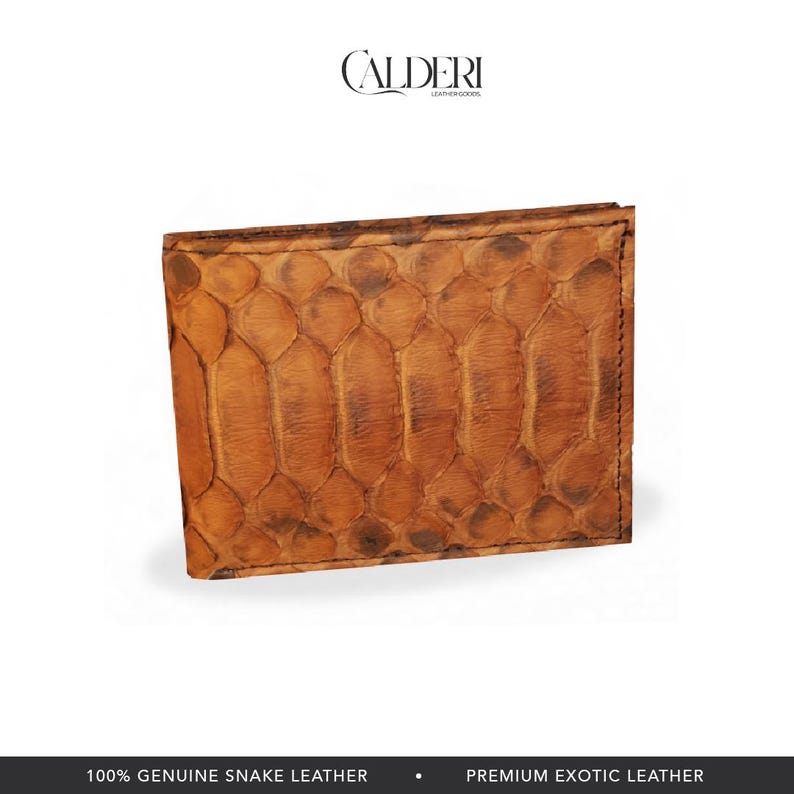 May include: A brown bi-fold wallet made of genuine snake leather. The wallet has a textured, scale-like pattern and a rectangular shape. The brand name "CALDERI" is visible at the top. The bottom of the image reads "100% GENUINE SNAKE LEATHER" and "PREMIUM EXOTIC LEATHER."