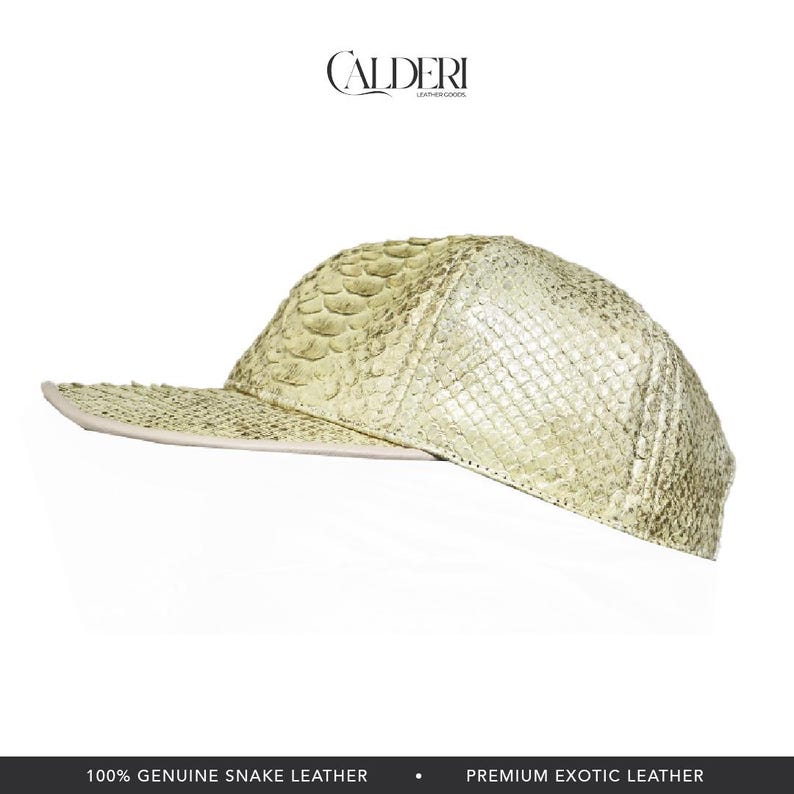 May include: A light green, textured baseball cap made of genuine snake leather. The cap has a flat peak and a structured crown. The brand name "CALDERI" is displayed at the top. The bottom of the image reads "100% GENUINE SNAKE LEATHER" and "PREMIUM EXOTIC LEATHER."