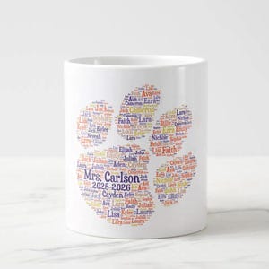 May include: White ceramic mug featuring a paw print design filled with names in various colors. The text "Mrs. Carlson 2025-2026" is also visible. A personalized gift idea.