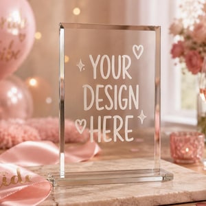 May include: A clear rectangular acrylic sign with a beveled edge and a matching base. The front surface features white etched text that reads YOUR DESIGN HERE, accompanied by two small heart icons and two four-pointed star symbols.